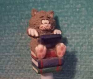 Katze, auf einem Stapel Bücher sitzend und auf einem Laptop tippend