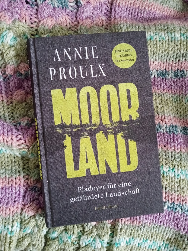 Heute möchte ich ein Buch empfehlen, in dem es um die Sümpfe, Moore und Feuchtgebiete der Welt geht: Moorland von Annie Proulx. Das Buch ist in einem dunklen Grau mit weißer und gelber Schrift. Es ist eine Moorlandschaft angedeutet.